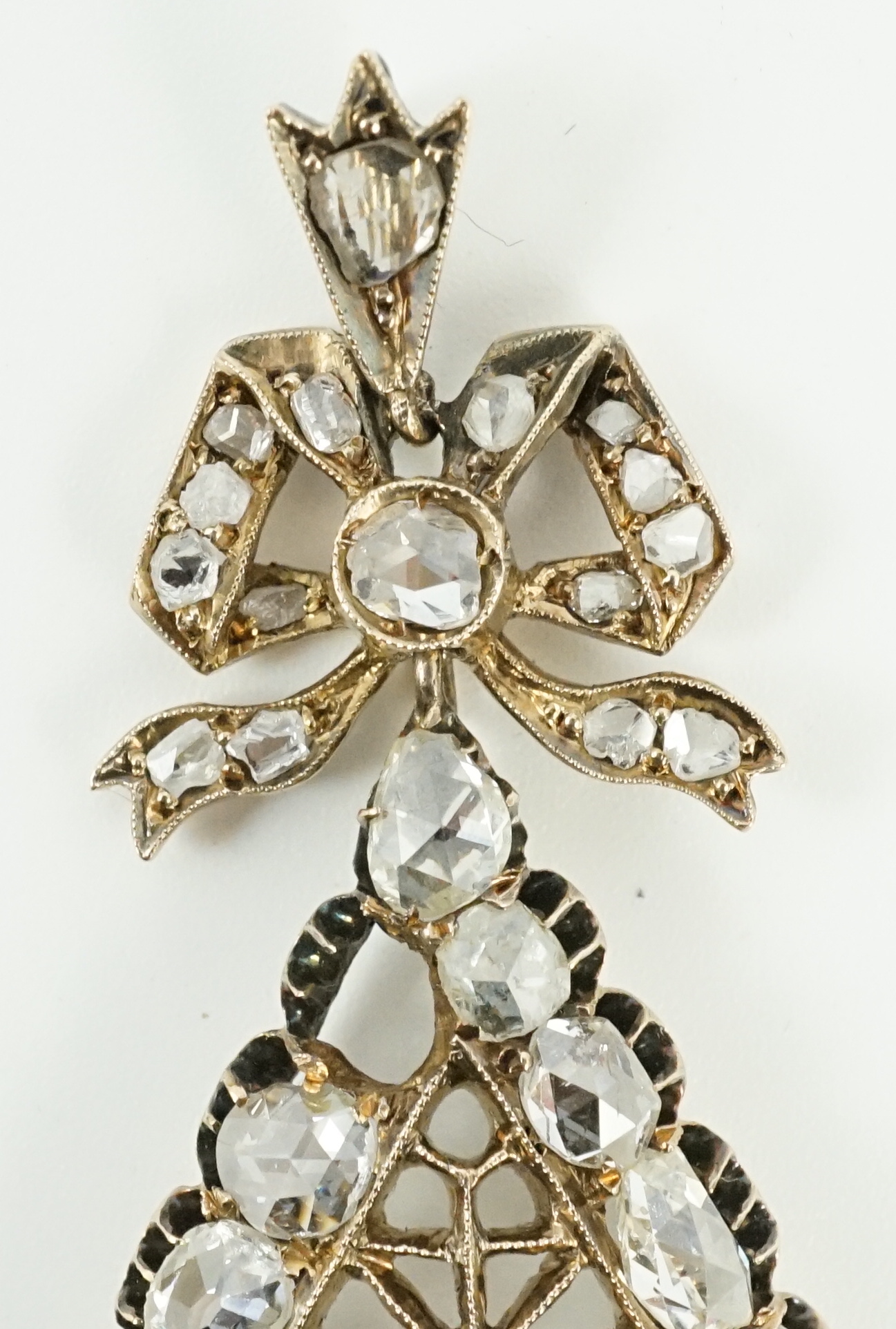 An early 19th century gold and rose cut diamond cluster set pear shaped drop pendant, with ribbon bow bale